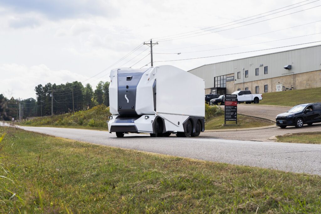 A driverless truck heads out onto the road from a light industrial estate