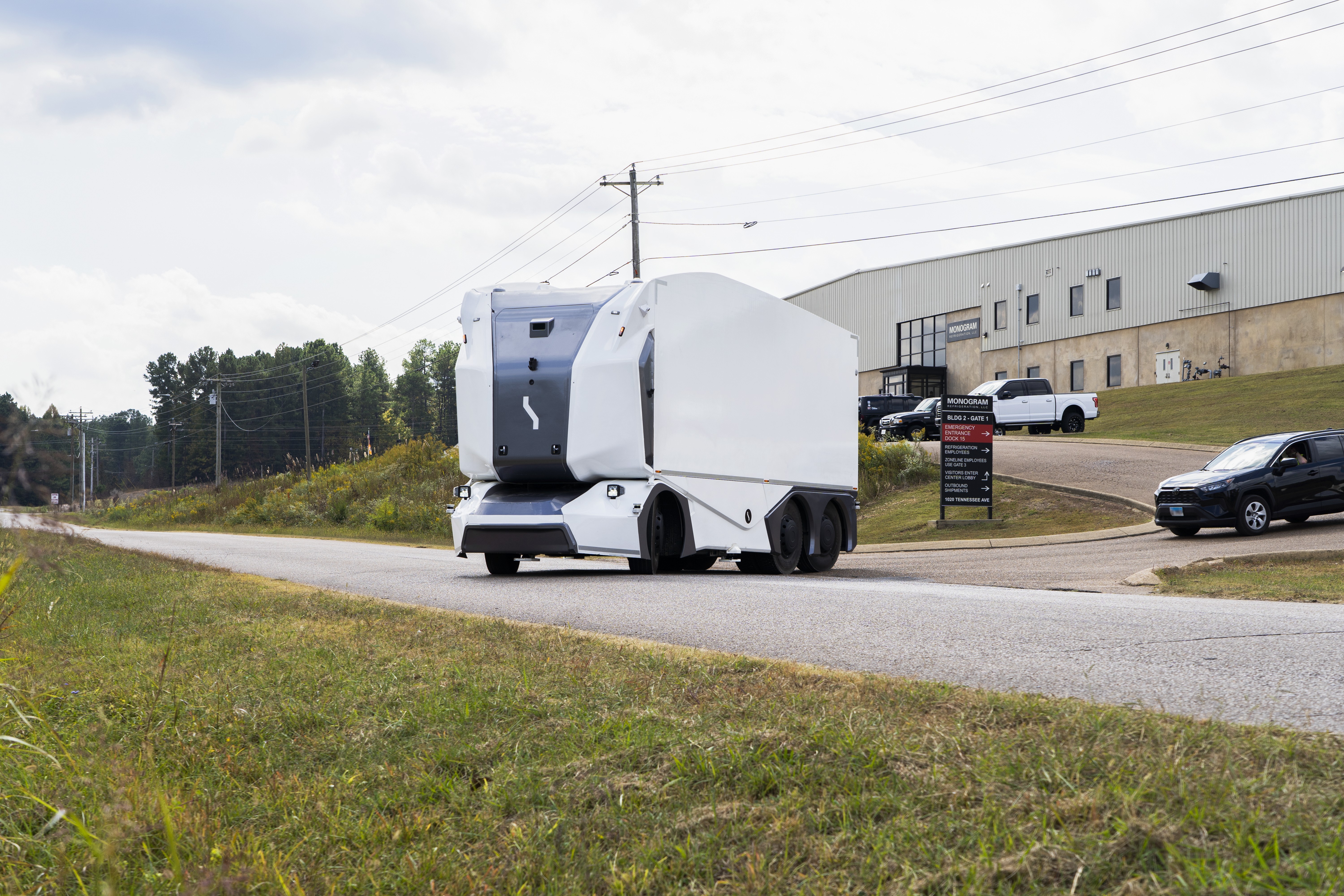 A driverless truck heads out onto the road from a light industrial estate