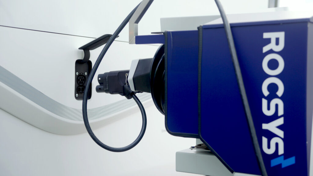 A Rocsys charging robot extends its plug towards the EV charge port of a cargo truck.