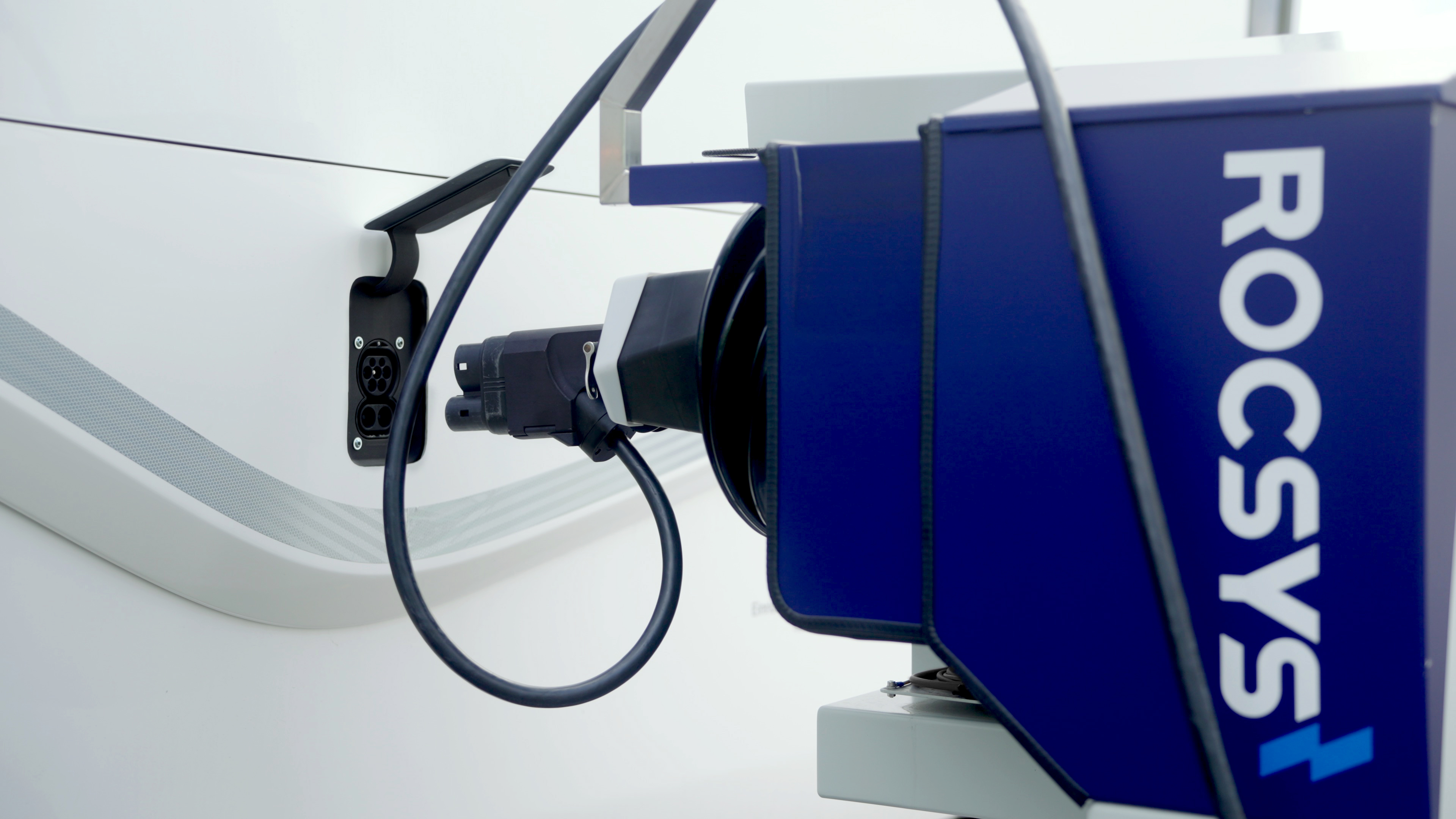 A Rocsys charging robot extends its plug towards the EV charge port of a cargo truck.