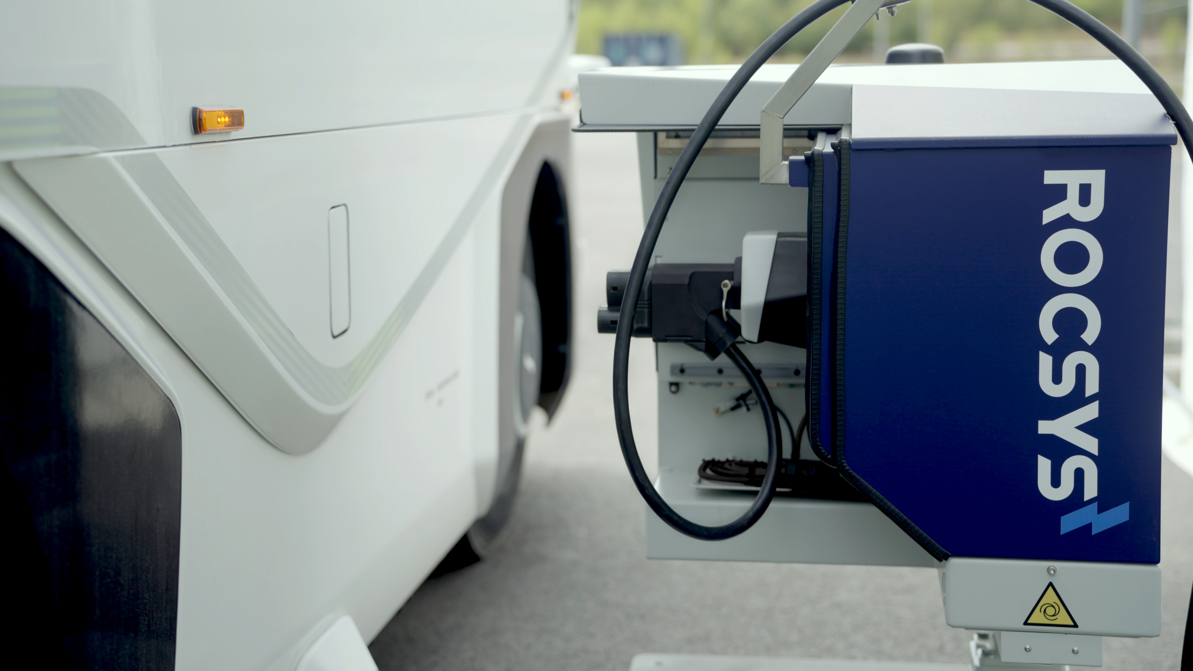 A Rocsys charging robot extends its plug towards the EV charge port of a cargo truck.