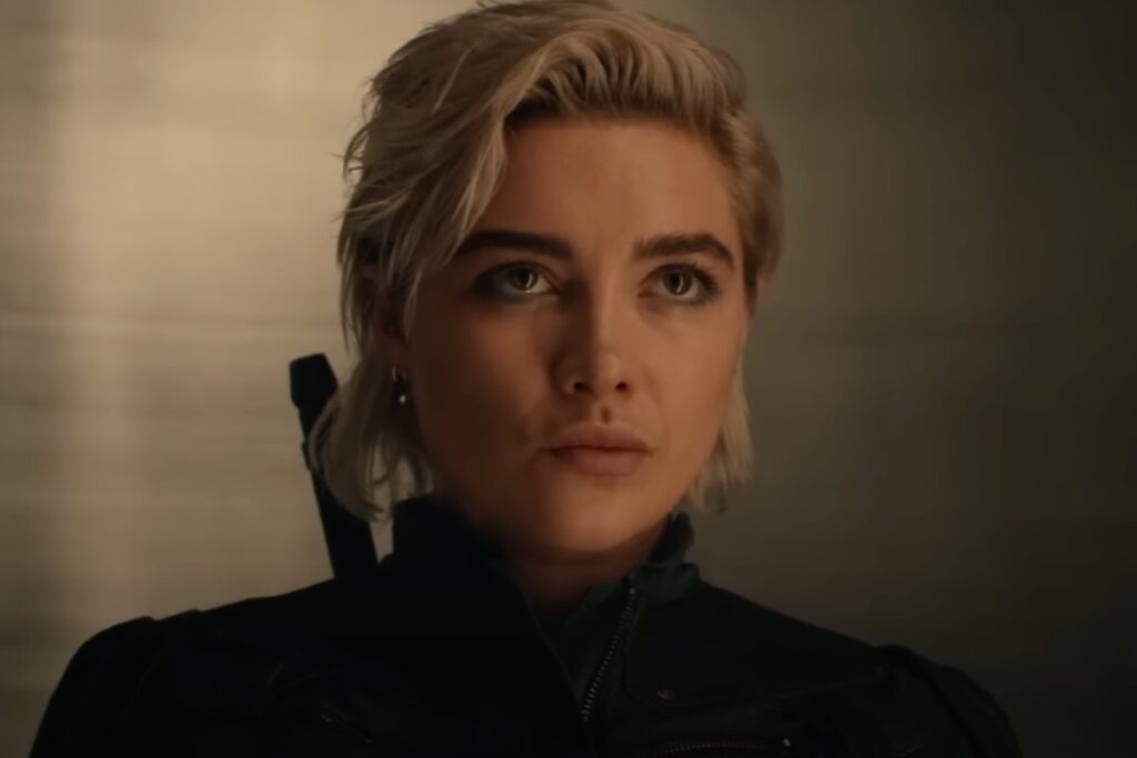 intense looking woman with short blonde hair dressed in a black action suit