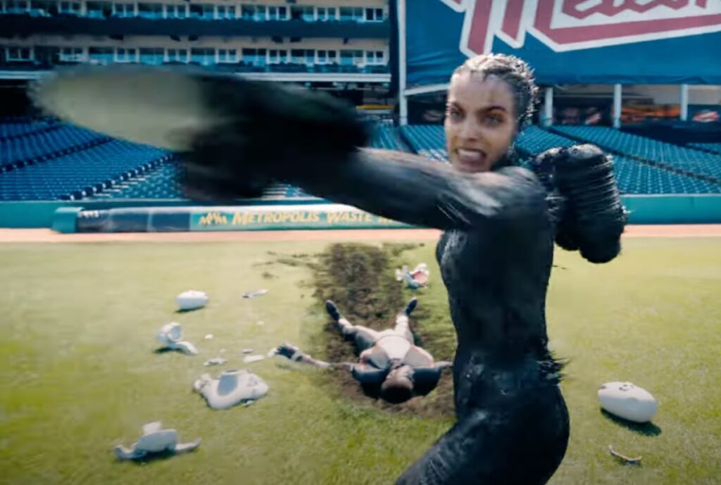 fierce woman in black spandex throwing a sharp metal disk on a football field.