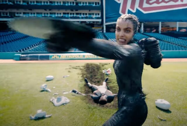 fierce woman in black spandex throwing a sharp metal disk on a football field.