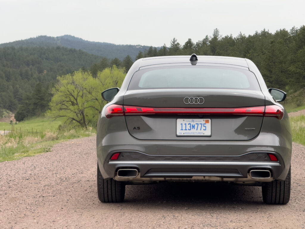 Audi A5 seen from behind, with tree-covered mountains in the background.