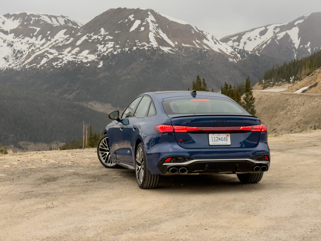 Audi S5 parked facing away from the camera, with snowy mountains in the background.