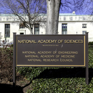 Image of a science in front of a marble building, declaring that the building hosts the National Academies of Science.