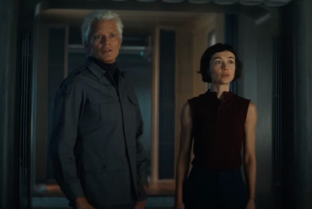 older white haired man standing next to a young woman by a doorway