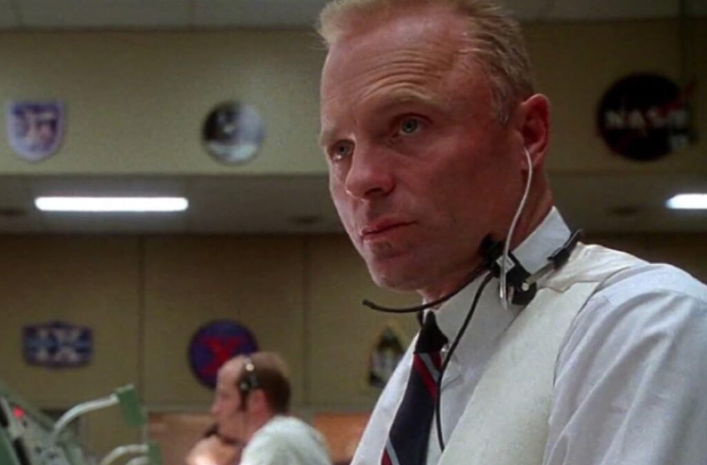 man with a crew cut in dress shirt and tie with comms headphones and mic on his head