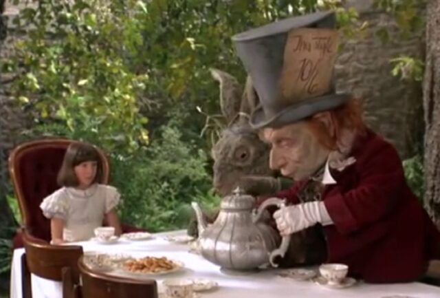 Young dark-haired girl with a bob in a white dress sitting down for tea with a a giant March Hare and the Mad Hatter