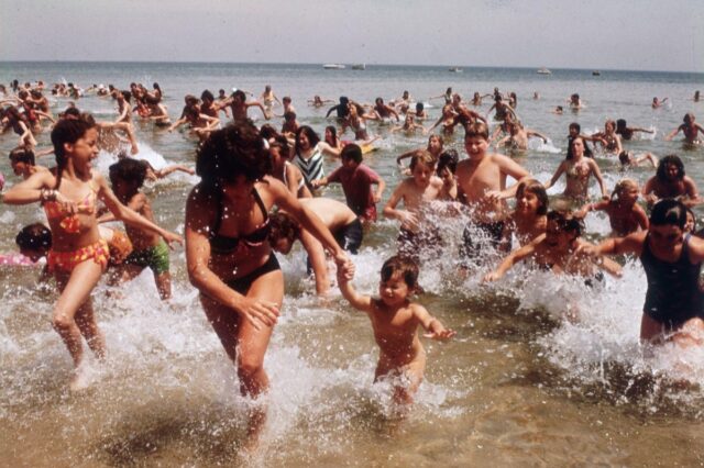 crowds of bathers running out of the water back onto the beach