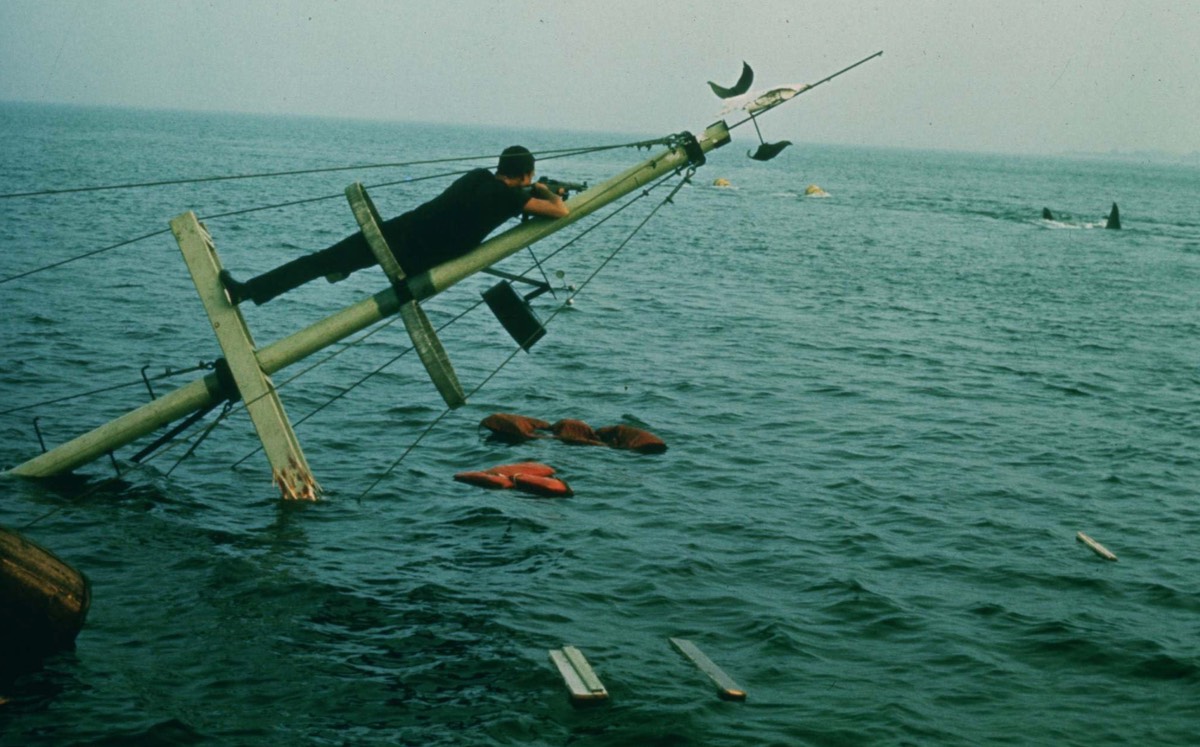 man clinging yo a boat mast sticking out of the water