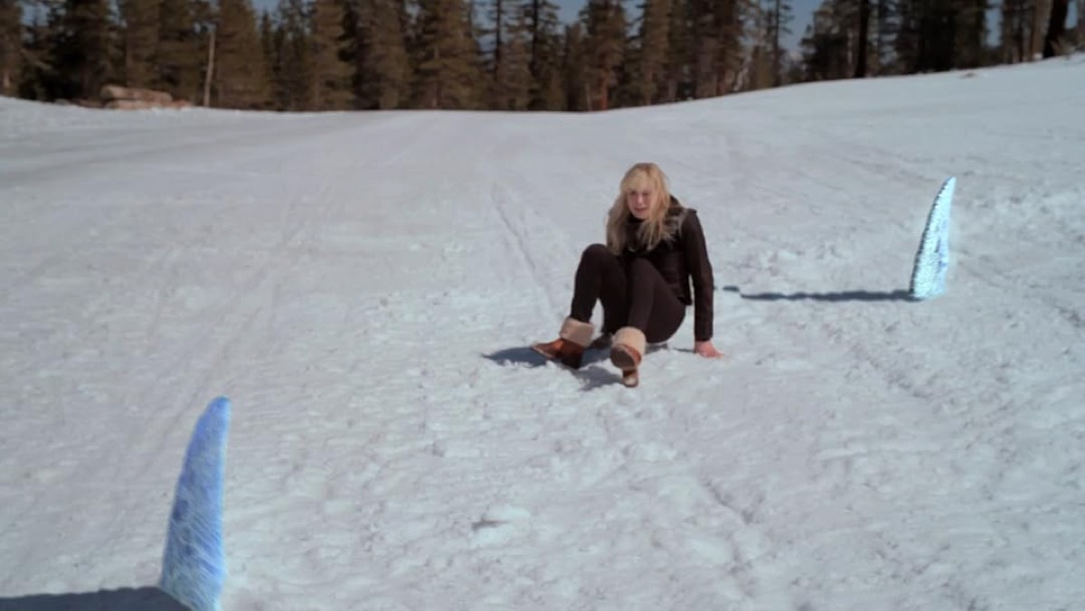 female skier sitting on the snow was shark fins poke out from under that snow.