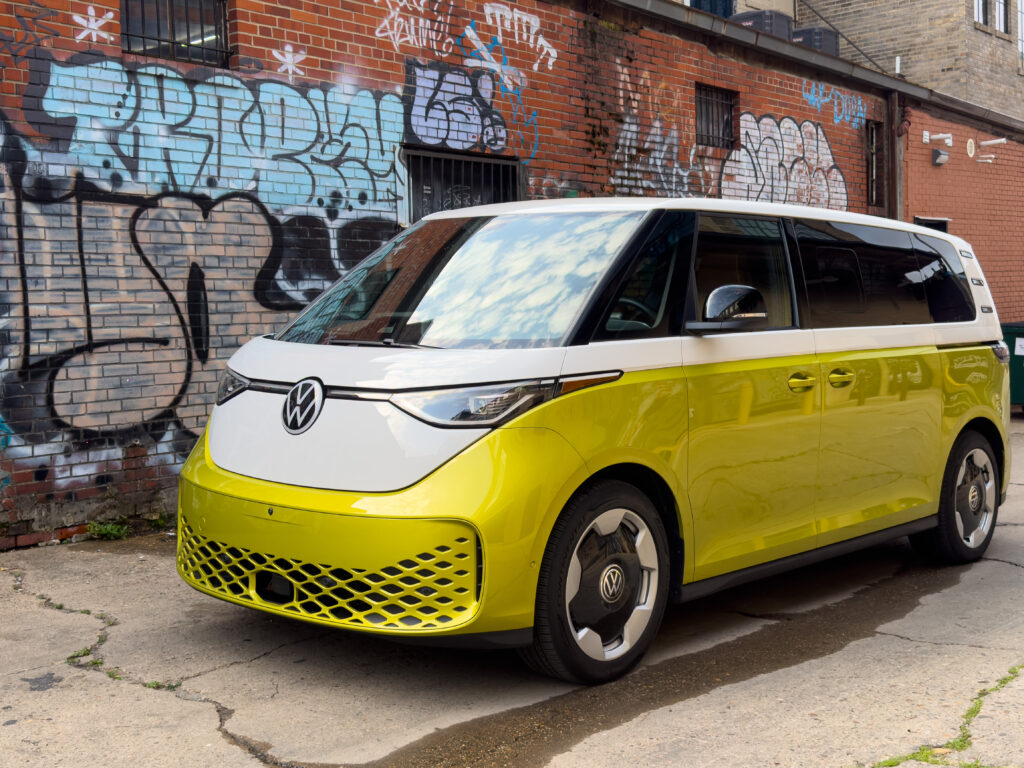 VW ID Buzz seen parked in an alley with graffiti, from the front 3/4s