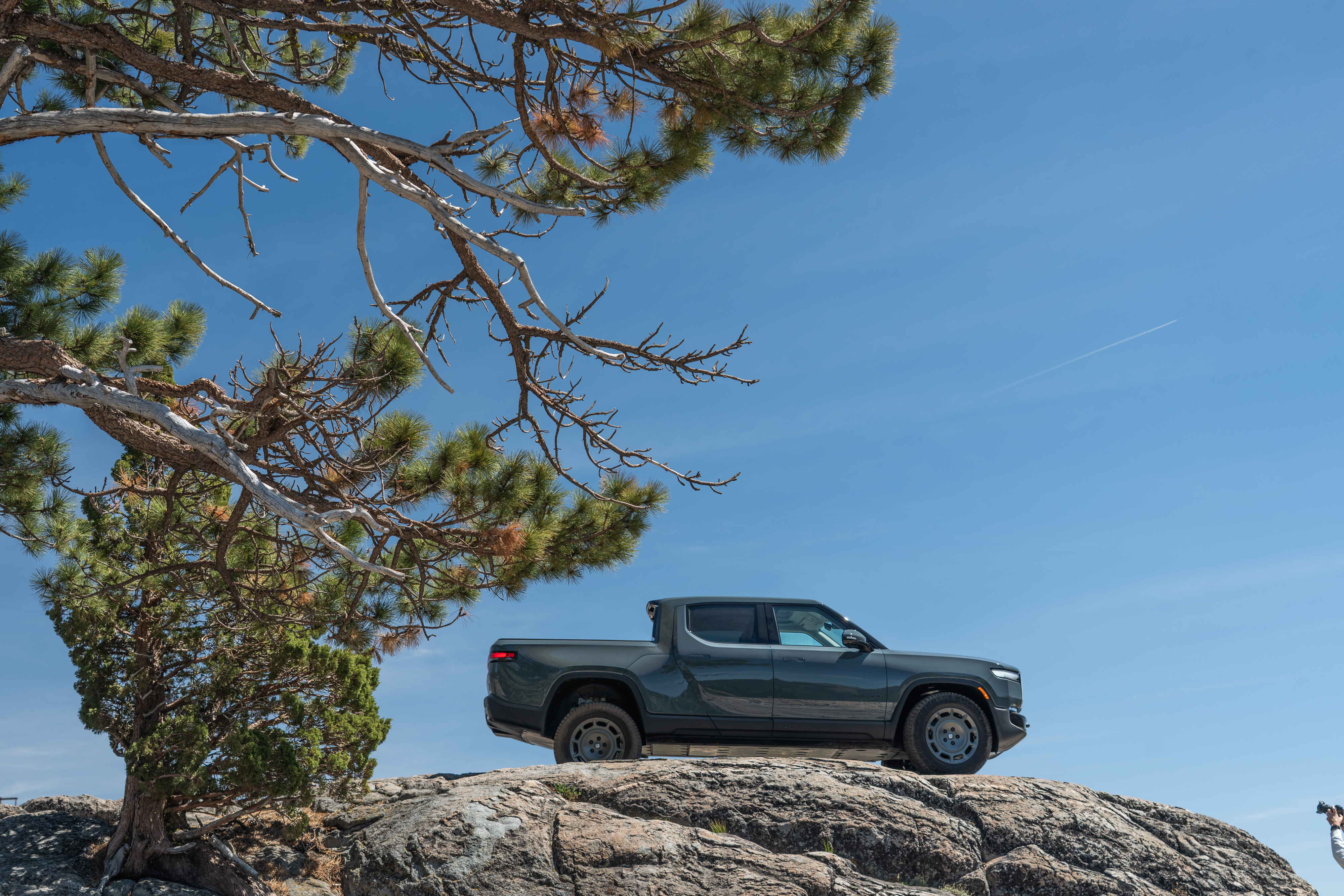 A Rivian R1T parked atop a rock outcrop