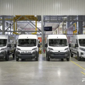 A row of four white Stellantis vans in a factory