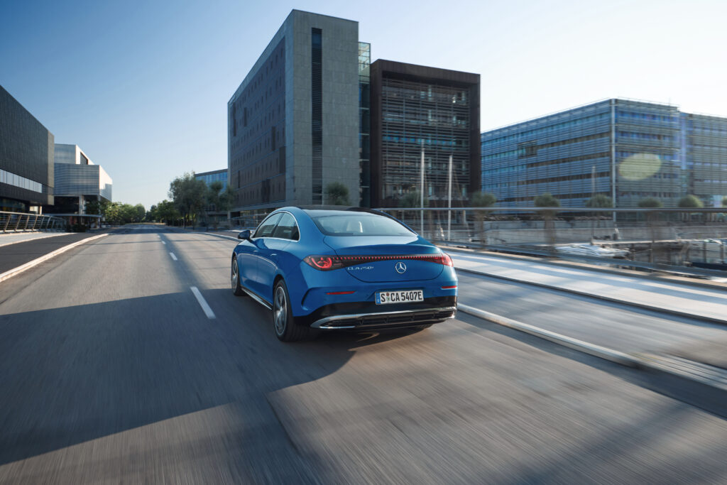 A blue Mercedes CLA drives away from the camera in a city