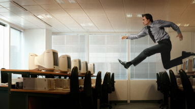 Photo of someone running though the air to reach a computer.