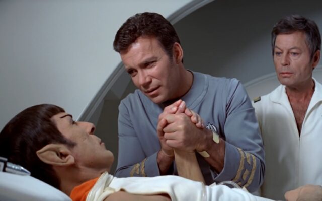 Spock întins în Golful bolnav, în timp ce Kirk își ține mâna tandru la noptieră