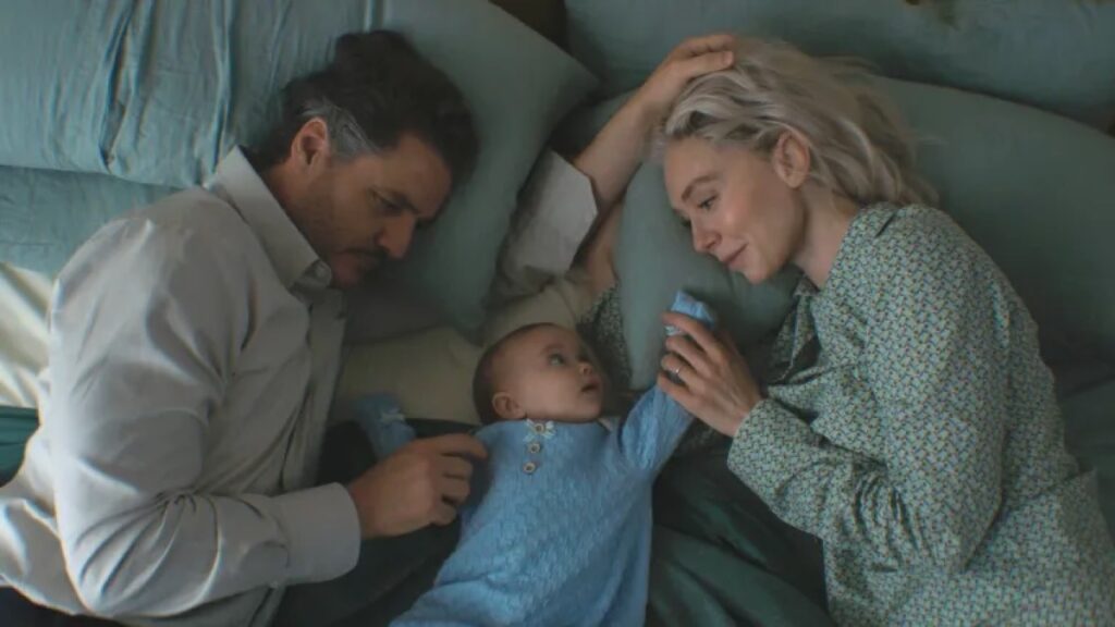 man and woman lying on a bed facing inward toward the newborn baby between them