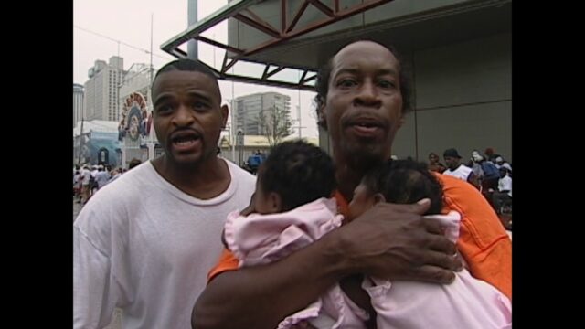 New Orleans resident Kevin Goodman holds his two baby nieces while seeking help from reporters in the face of dire conditions at the Convention Center.