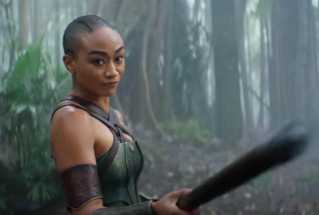 Black woman in black fighting garb wielding a spear.