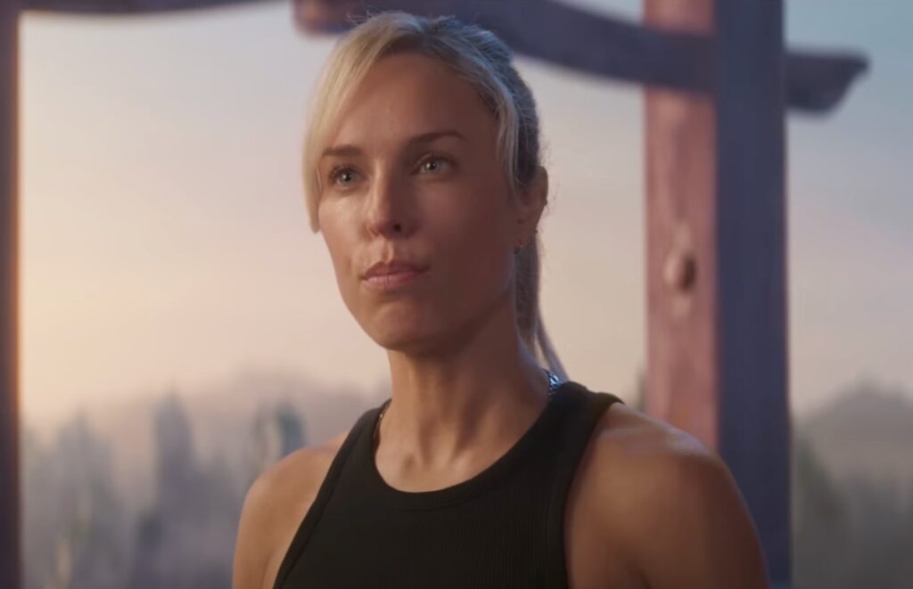 blonde woman in tank top pursing her lips.