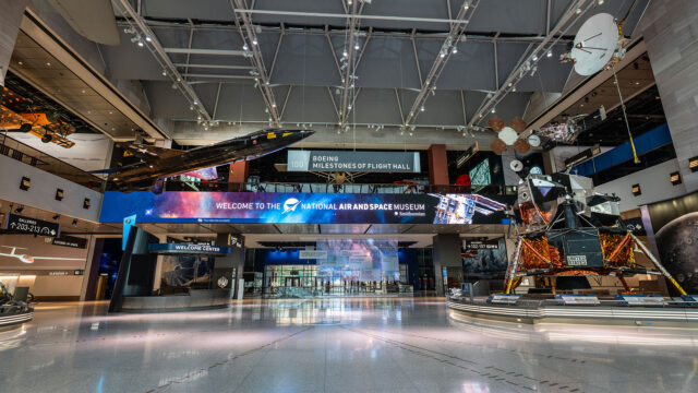 a museum gallery with air and spacecraft displayed on the terrazzo floor and suspended from the ceiling