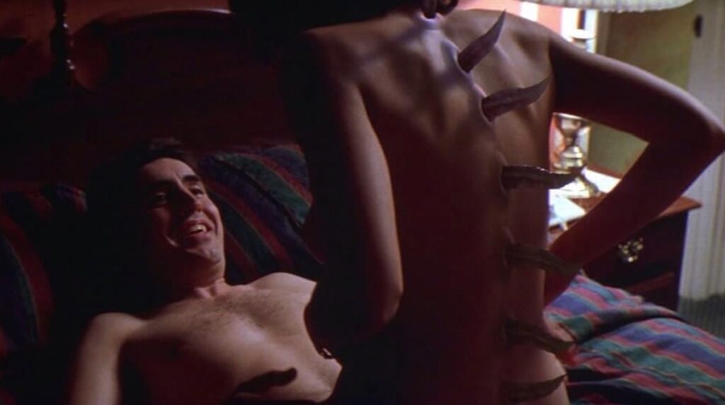 Man lying on his back with a woman astride, post-coitus; woman has spikes starting to poke out of her back