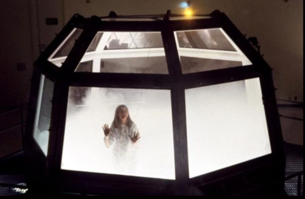 show of young girl imprisoned in a glass enclosure filling up with gas.