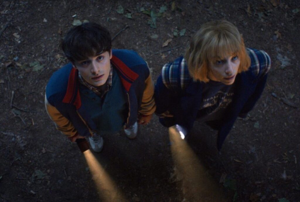 young man and young woman with flashlights looking up with growing alarm.