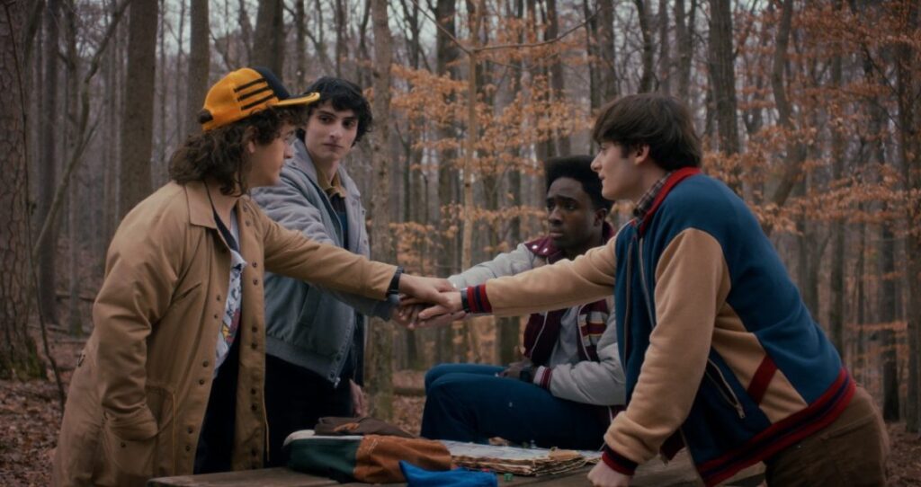 four young men in the woods putting their hands in the center as a bonding sign.
