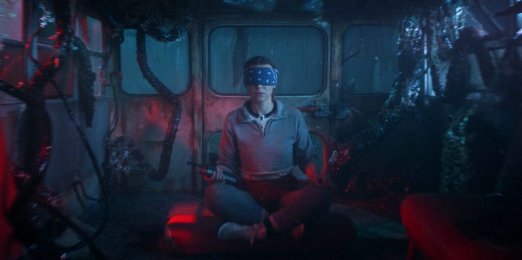 young woman blindfolded, sitting in an abandoned vehicle with dark purplish hues surrounding her