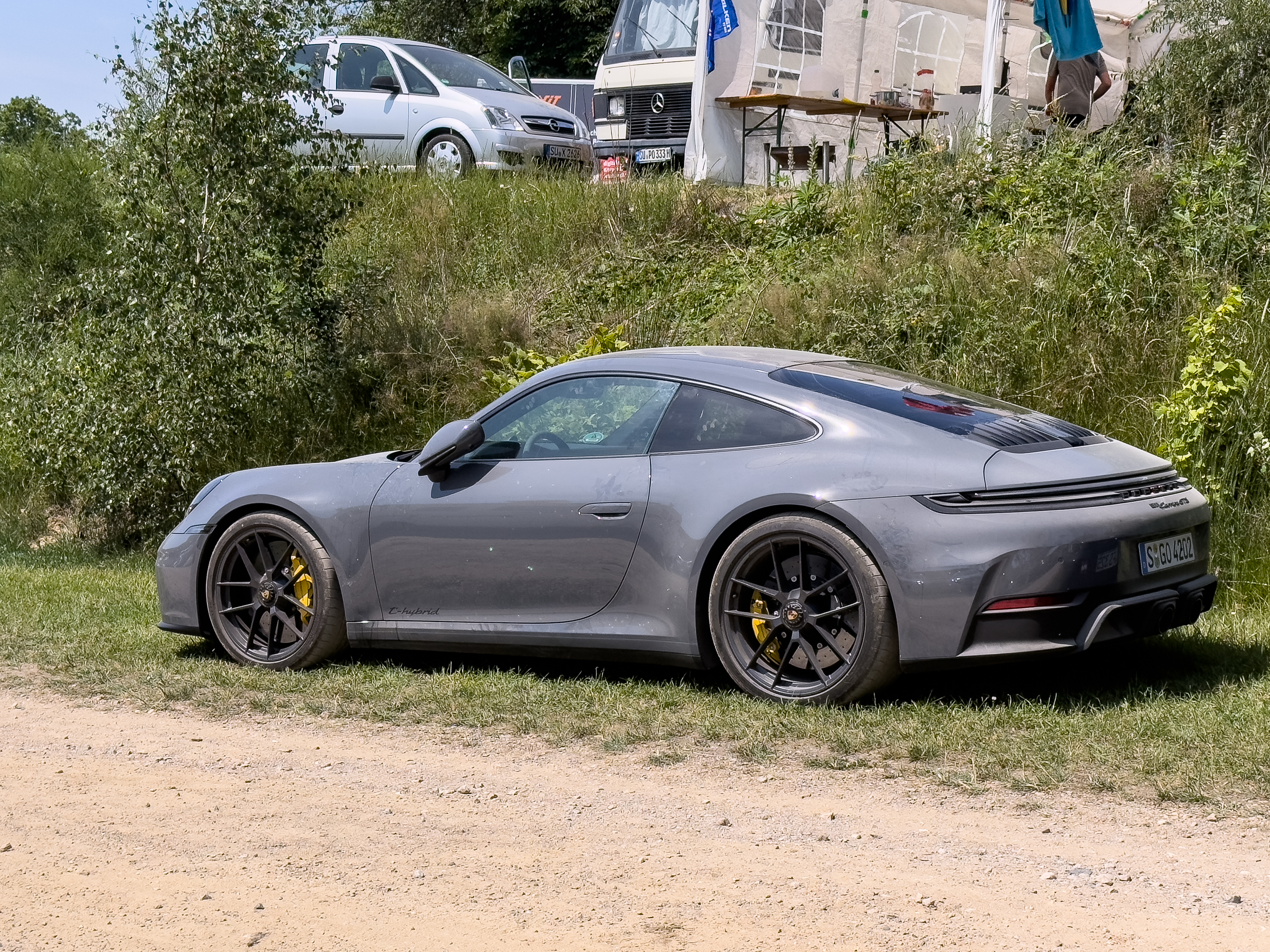 A grey Porsche 911 parked in a campsite