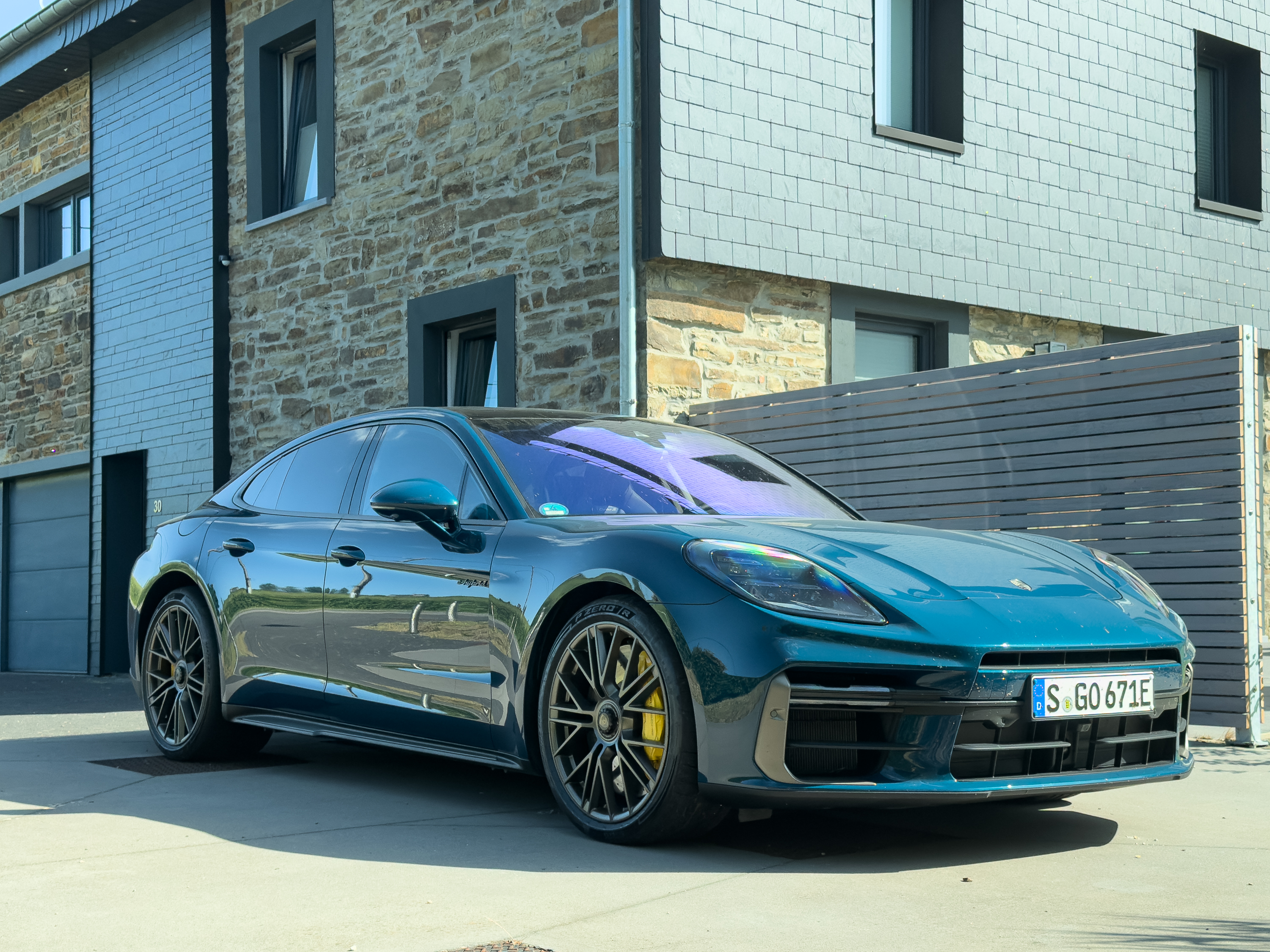 A blue Porsche Panamera Turbo S next to a farmhouse