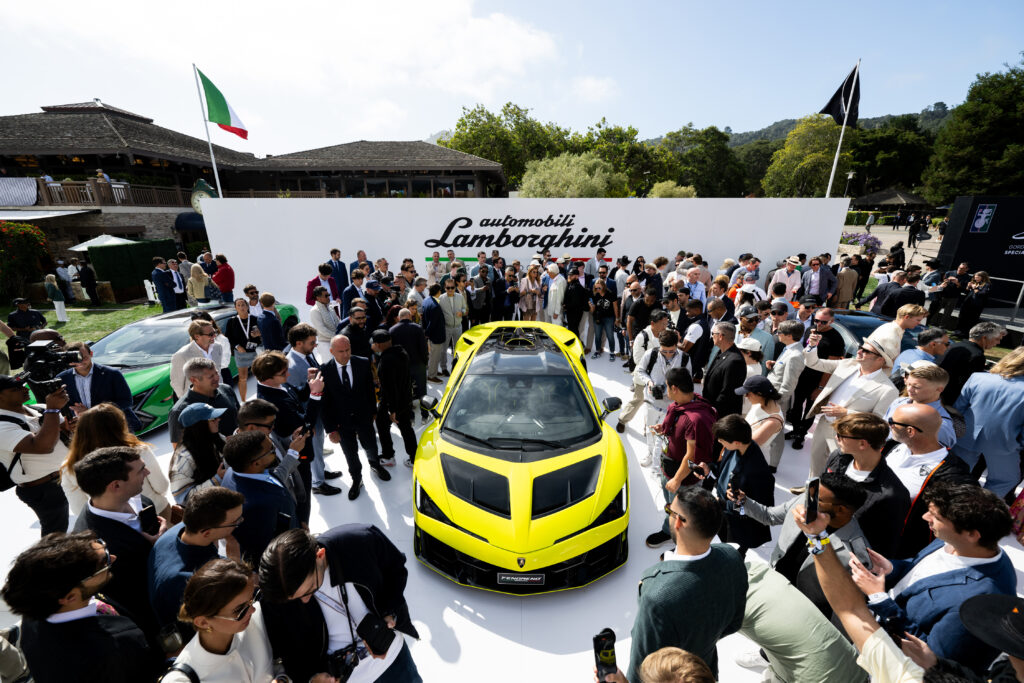 A lamborghini on a display stand, surrounded by people.