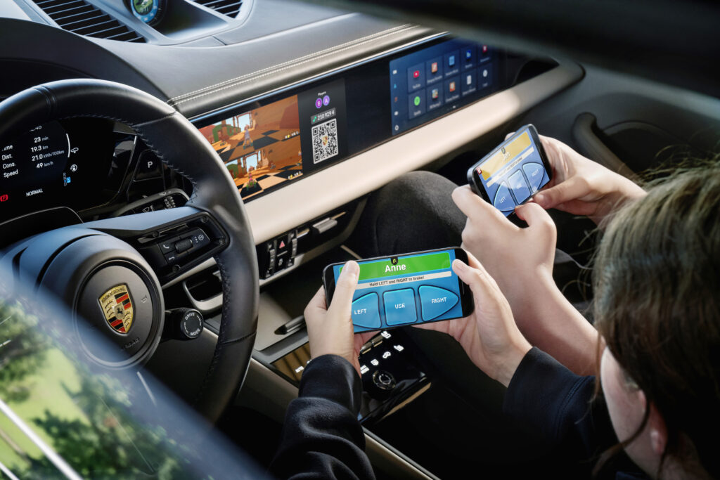 Due persone usano il telefono per giocare il punteggio aereo all'interno di Porsche Macan
