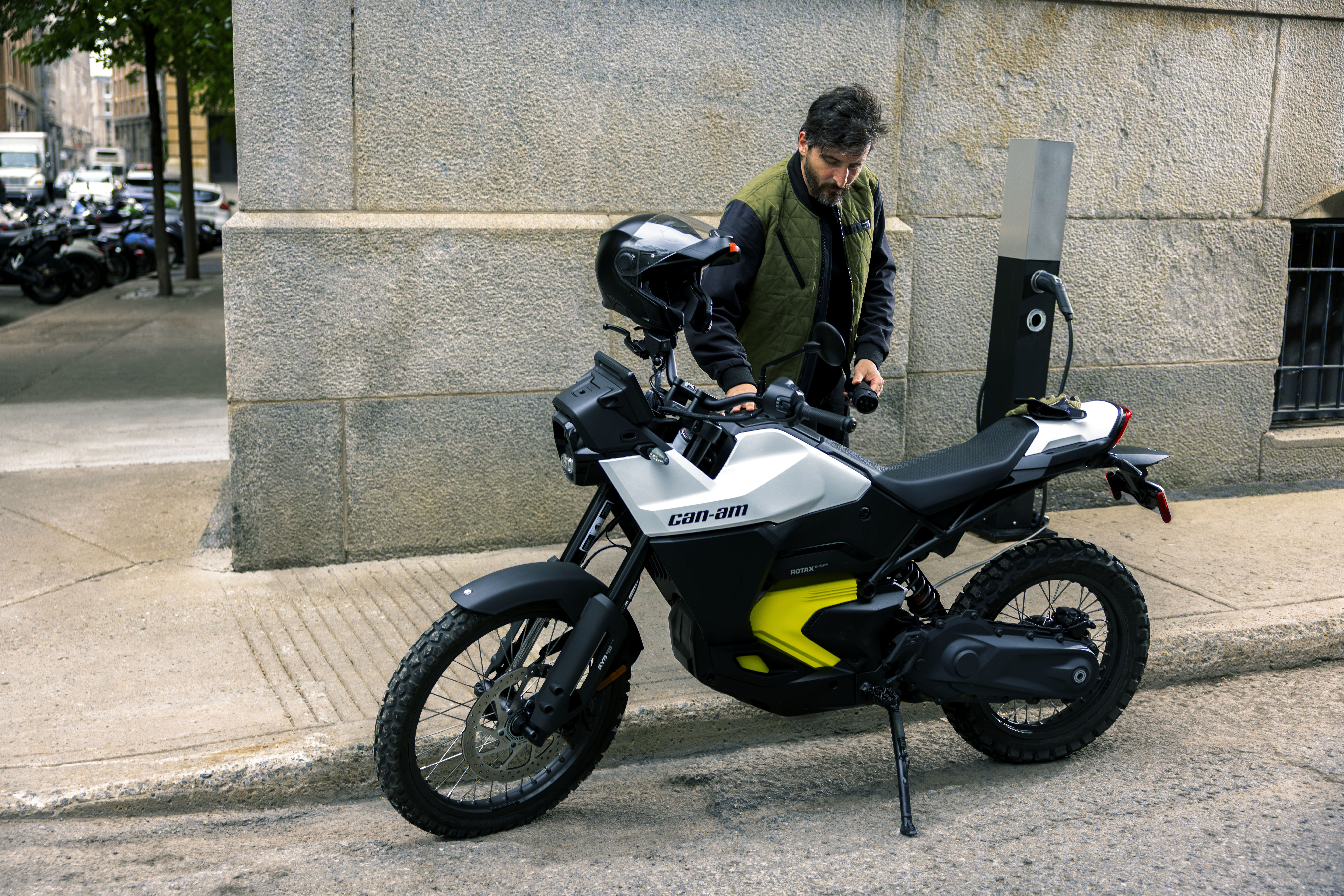 A man charges a Can-Am electric motorbike in the street.