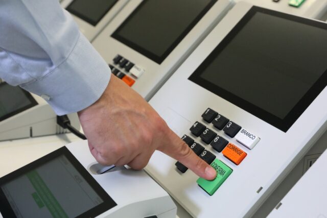 Brazilian voting machine showing a man's hand pushing the submit button