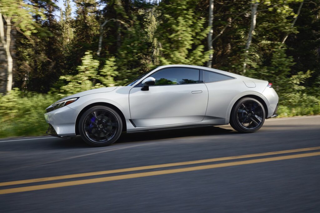 A white Honda Prelude drives past the camera