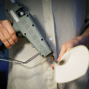 A person holding a grey industrial glue gun.