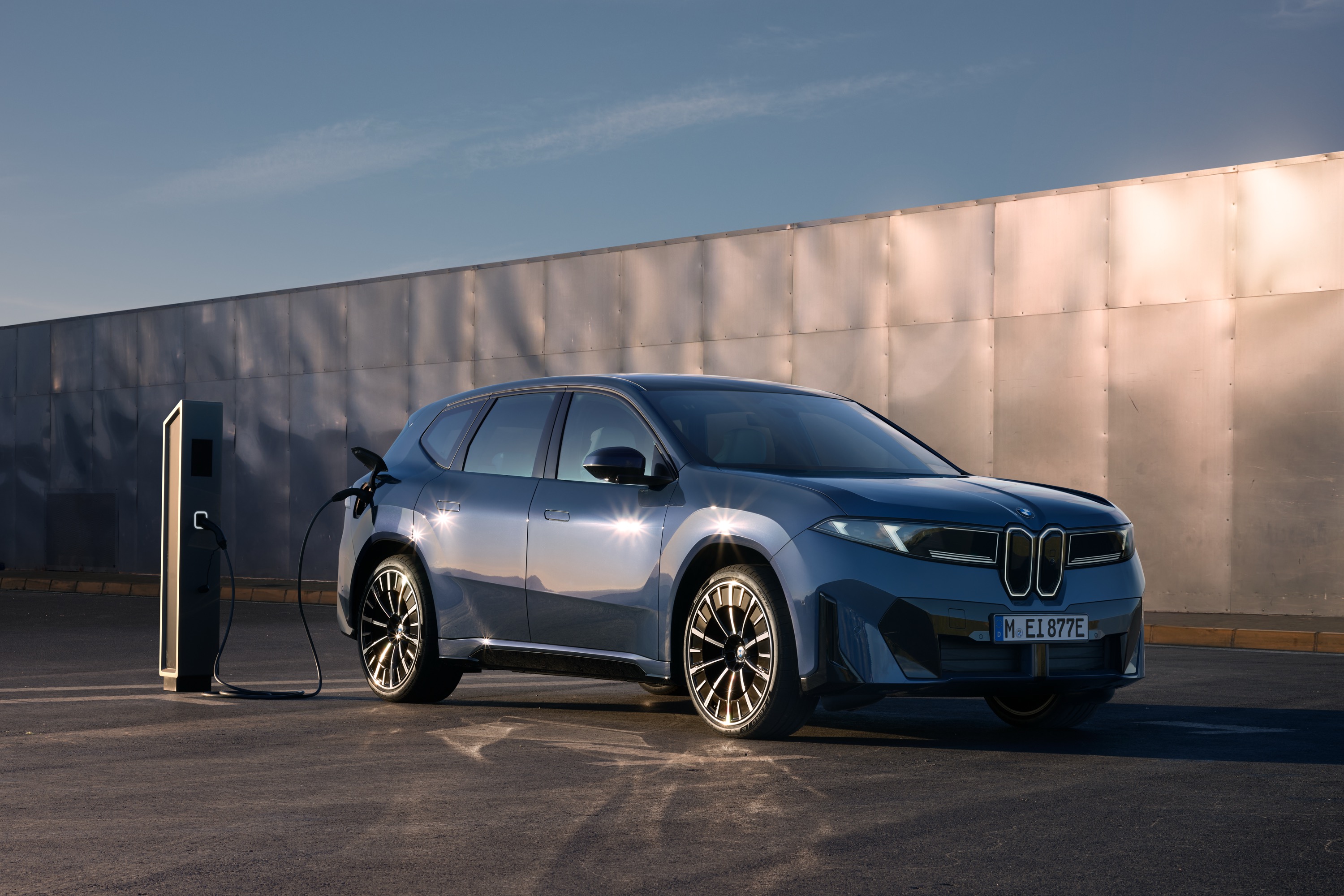 A BMW iX3 is parked, charging