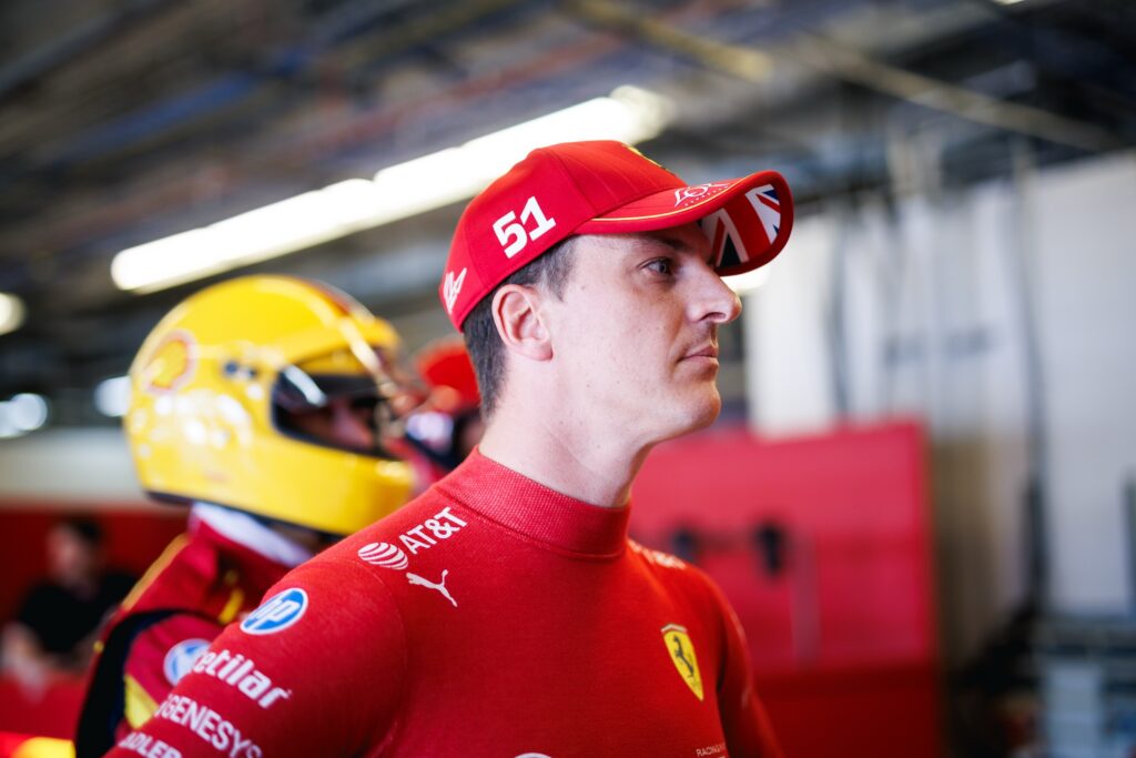 A racing driver wearing a red ball cap