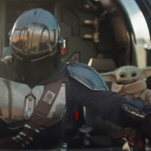 mandalorian in full armor seated in cockpit of spacecraft with grogu by his side