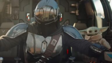 mandalorian in full armor seated in cockpit of spacecraft with grogu by his side