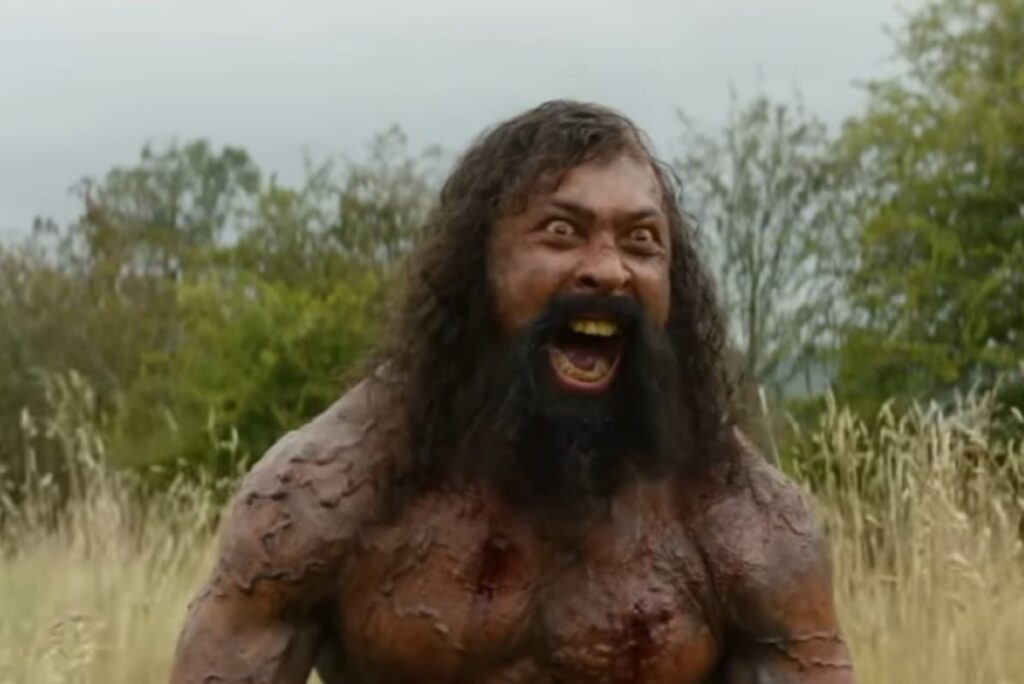 Zombie de cabello salvaje de ojos salvajes, con el pecho desnudo que da un grito de guerra