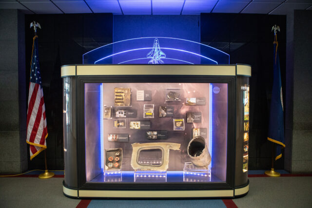 a glass display case holds artifacts from a fallen space shuttle
