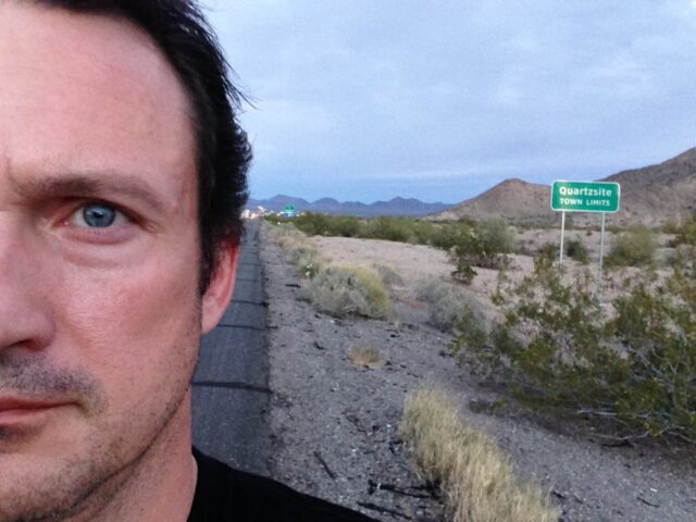 Avellone stands in front of a road sign on a highway