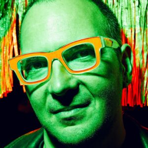 head shot of the author, wearing yellow glasses; entire shot bathed in green hues