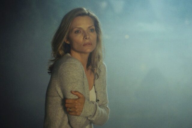 Beautiful blond woman in a sweater standing in the fog hugging herself to keep warm